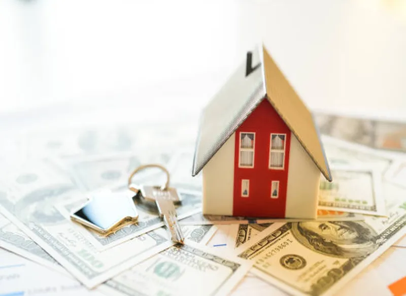 Mini home model with keys on cash representing quick sale
